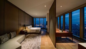 A modern bedroom with a large bed, a desk, and a sofa. It features large windows with a city view. - Nanjing Golden Eagle International (Nanjing)