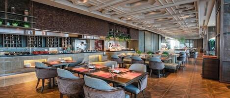 A modern restaurant with a geometric ceiling design, a bar area, and a variety of seating options including tables and chairs.