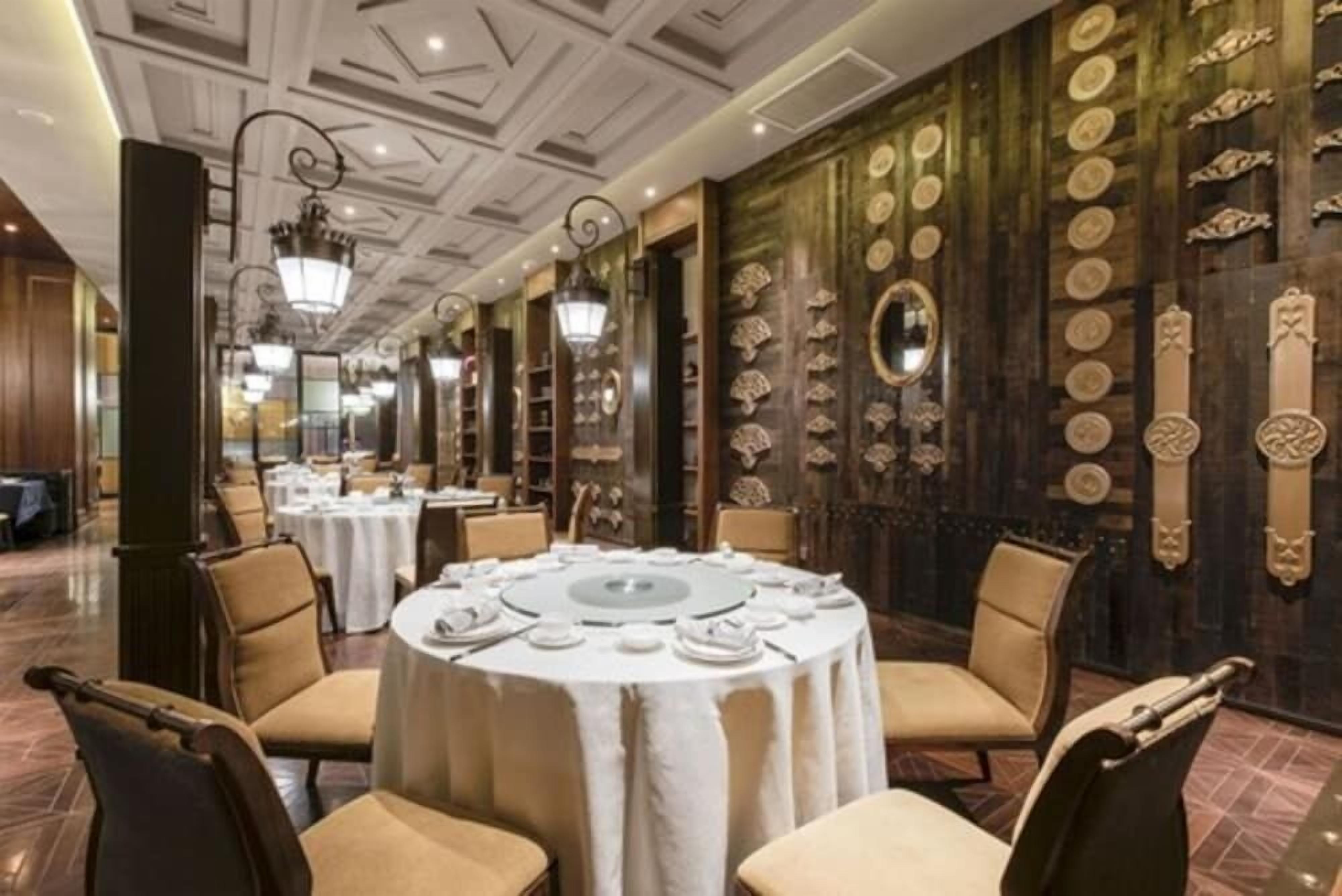 A formal dining area with round tables, chairs, and ornate wall decorations.