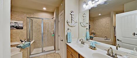 A modern bathroom with a glass shower enclosure, a large vanity with a sink and mirror, and decorative wall art.