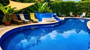 A swimming pool with steps leading into it, surrounded by lounge chairs and a potted plant. - Breathtaking Ocean Vistas, Jungle Bliss, Walk to Eateries & Beach, Fast Internet (Manuel Antonio)