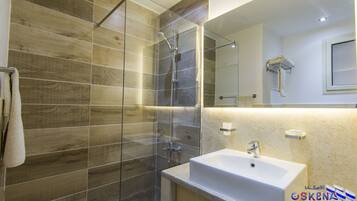 A modern bathroom with a glass shower enclosure, a white sink, and a large mirror.