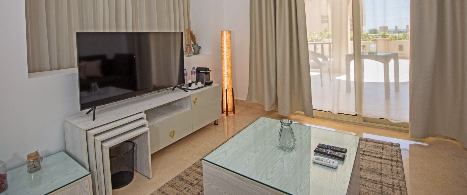 Ein modernes Wohnzimmer mit Flachbildfernseher, Glastisch und Kamin.