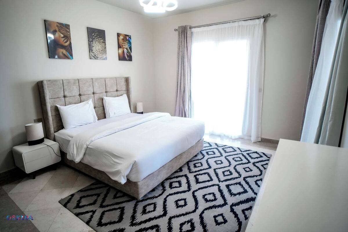 A bedroom with a large bed, bedside tables, and a patterned rug.