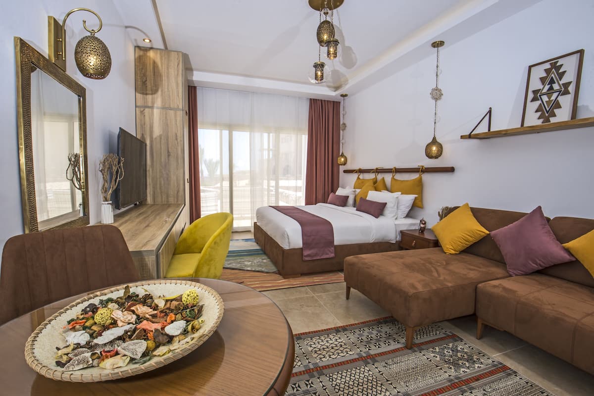 A hotel room with a bed, sofa, dining table, and a large decorative tray.