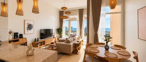 A modern living room with a sofa, coffee table, and dining area with a view of the ocean.
