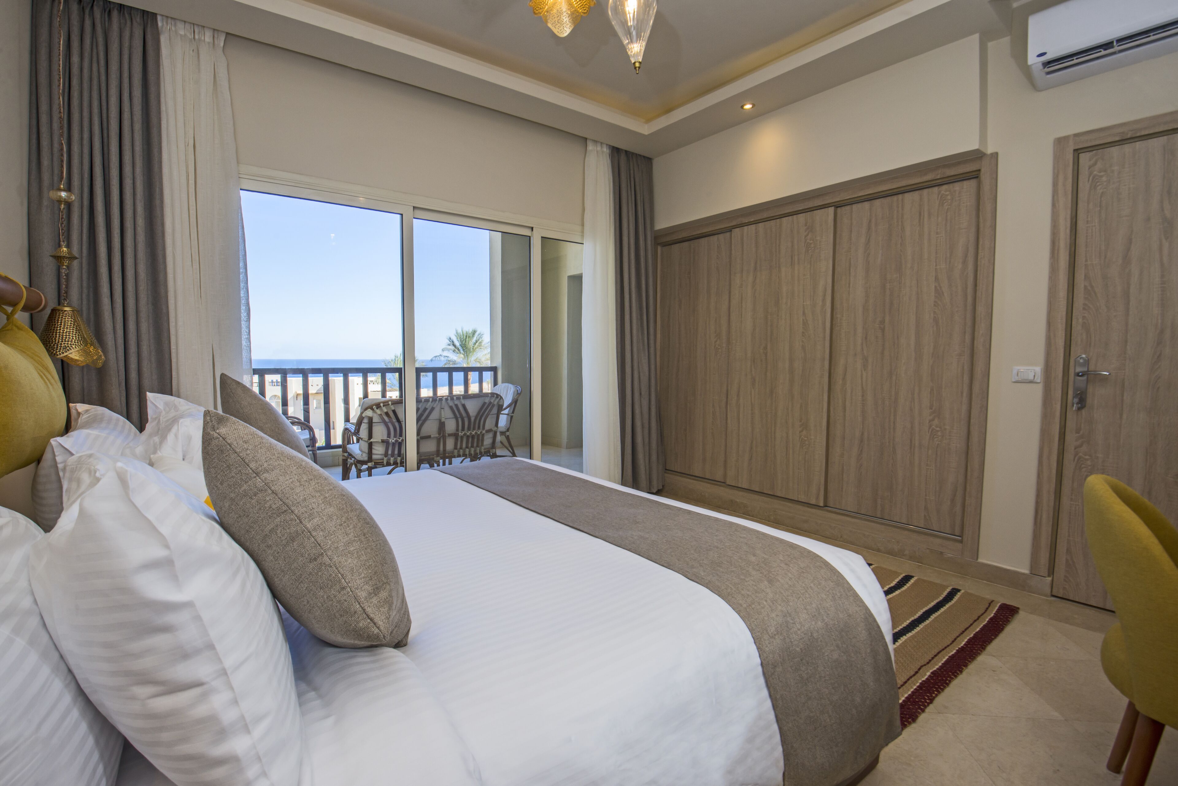 Una camera d'albergo con un letto grande, un balcone vista e un armadio.