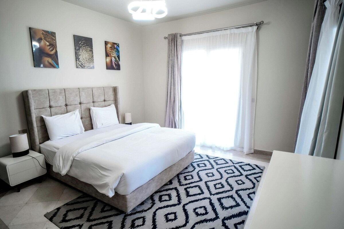 A bedroom with a large bed, bedside tables, and a patterned rug.
