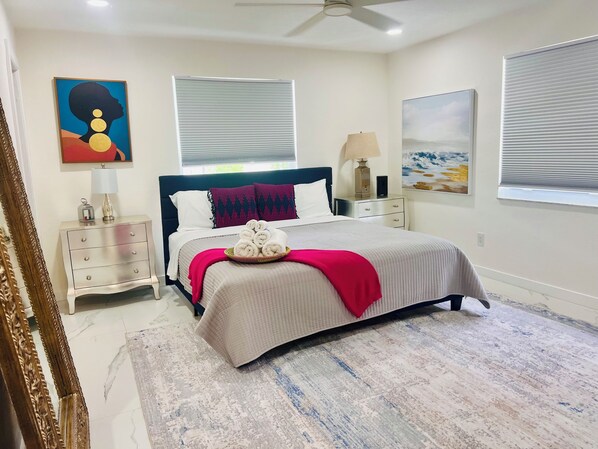 A neatly arranged bedroom with a bed, bedside tables, a lamp, and artwork on the walls.