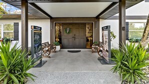 Un acceso cubierto con una puerta de madera, dos bancos de madera y un cartel.
