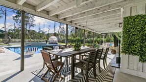Un patio cubierto con piscina, mobiliario exterior y vistas del paisaje circundante.