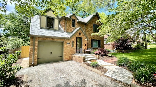 A two-story house with a garage, a front porch, and a well-maintained lawn. - Country Club Charm (Omaha)