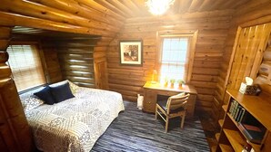 A log cabin bedroom with a bed, desk, chair, and a small bookshelf. - Country Club Charm (Omaha)