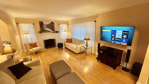A modern living room with a flat-screen TV, a fireplace, a sofa, a coffee table, and a lamp. - Country Club Charm (Omaha)