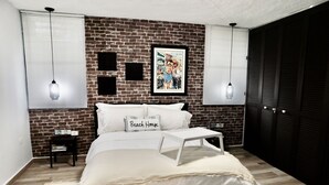 A bedroom with a brick wall, white bedding, a bedside table, and a framed picture on the wall. - AQUA VILLA steps from the beach (Luquillo)