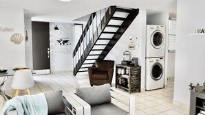 A modern living room with a staircase, a sofa, a coffee table, and a washing machine. - AQUA VILLA steps from the beach (Luquillo)