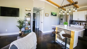 A modern kitchen with a central island, bar stools, and a dining area. - Newly constructed cabin on a quiet residential pond.  (North Pole)