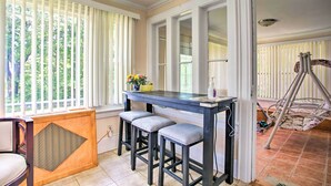 Eine Küche mit einem dunklen Holztisch, drei Barhocker und einem Fenster mit Jalousien.