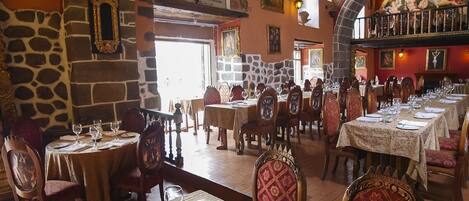 A restaurant with stone walls, wooden tables, and chairs.