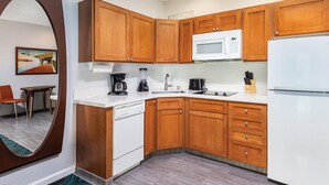 A modern kitchen with wooden cabinets, a white refrigerator, a microwave, a coffee maker, and a dishwasher.