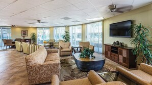 A spacious lobby with a large sofa, armchairs, a coffee table, and a television mounted on the wall.