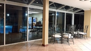 A spacious indoor area with a glass partition, several chairs, and a tiled floor. - Studio in Palm Springs 2 (Palm Springs)