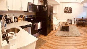 A modern kitchen with a microwave, stove, and dishwasher. There is a dining area with a table and chairs.