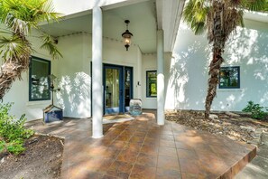A covered outdoor area with a tiled floor, a door, and a palm tree.