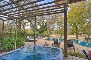 A covered outdoor area with a hot tub, lounge chairs, and a pool.