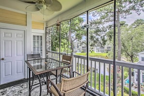 Relax on the covered porch with a glass table and wicker chairs, taking in the serene view of the lawn and water.