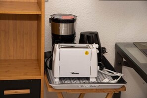 Une cuisine équipée d’une machine à café, d’un grille-pain et d’une cafetière posés sur un plan de travail.