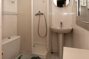 Un baño con inodoro, ducha con puerta de vidrio, lavamanos y espejo.