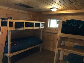 A bunk bed room with wooden walls and a window.