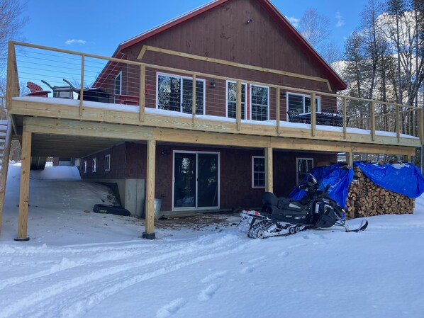 A two-story wooden house with a covered porch and a snow-covered deck.