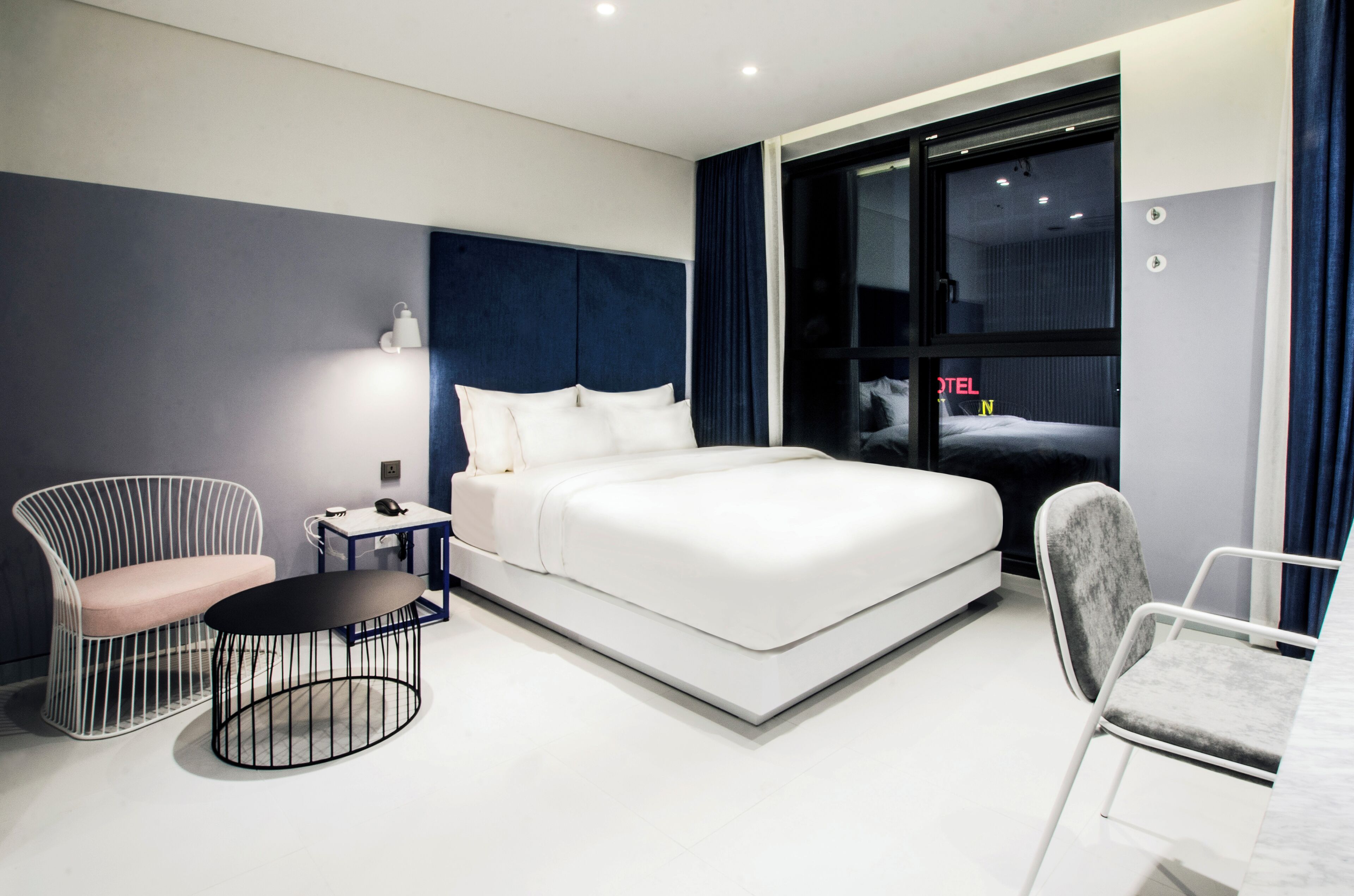 Una habitación de hotel moderna con una cama grande, un escritorio, una silla y una mesa redonda.