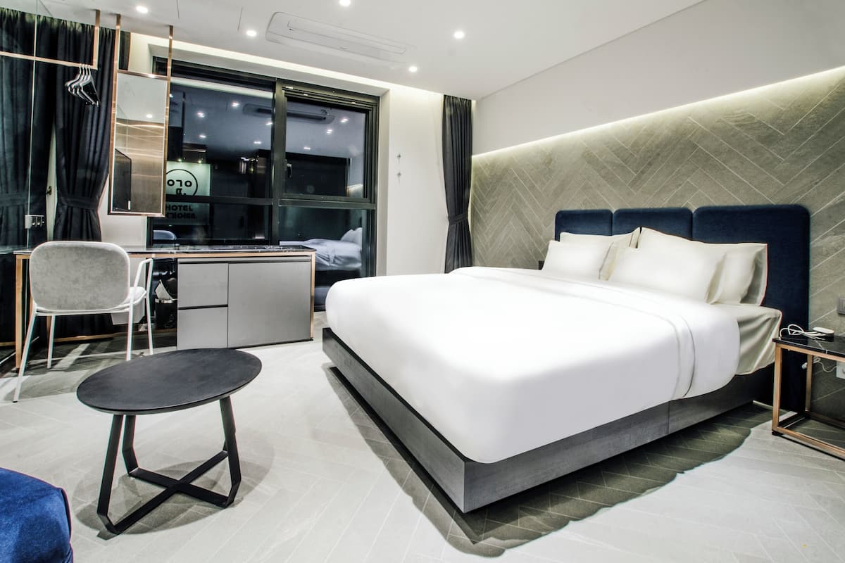 Une chambre d’hôtel moderne avec un grand lit, un bureau, une chaise et une petite table.