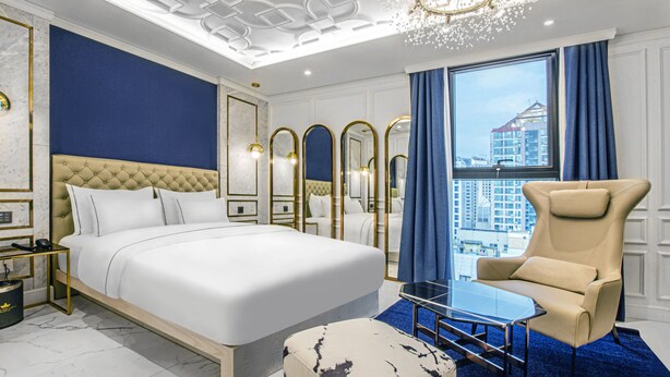 Una habitación de hotel moderna con una cama grande, zona de estar y vistas a la ciudad.