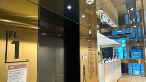 Interior de un ascensor con detalles metálicos, un indicador de piso y un panel informativo de plantas.