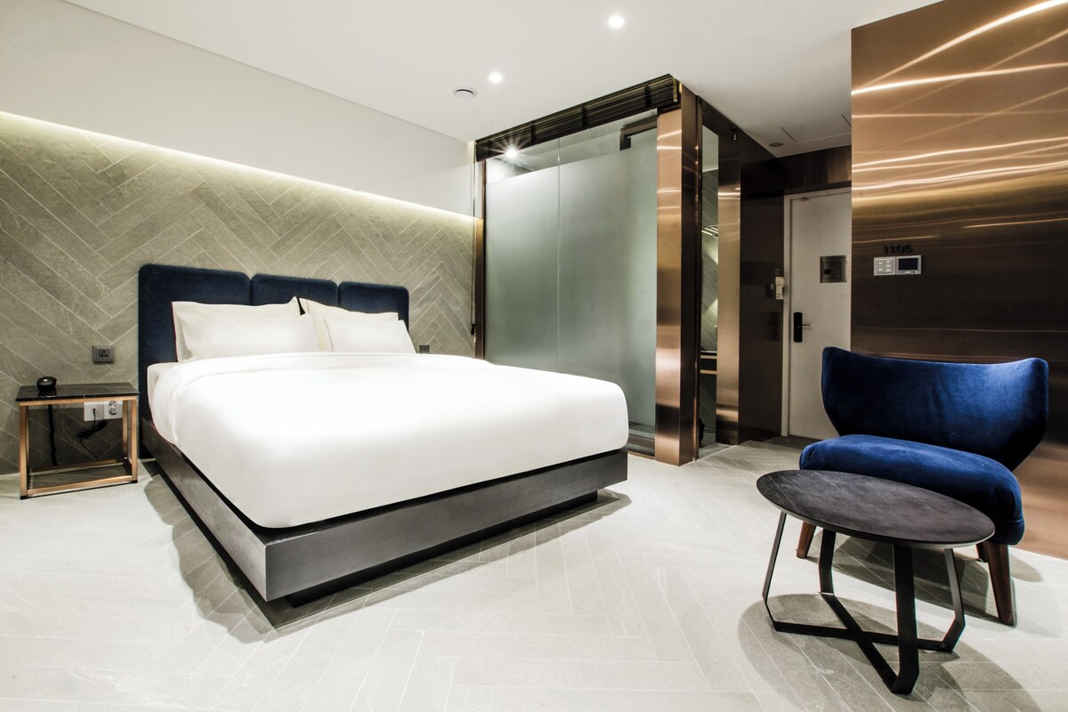 A modern bedroom with a large bed, a desk, and a chair.