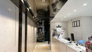 Zona de recepción de un hotel con un árbol de Navidad, un mostrador de recepción y una alfombra con el logotipo del hotel.