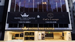 Un hotel moderno con un diseño vertical llamativo, que muestra la señalización 'Hotel The Castle' y 'CoCo Lounge'.