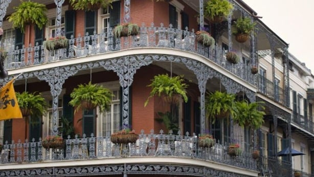 Un edificio de varios pisos con balcones ornamentados, ventanas grandes y macetas colgantes.