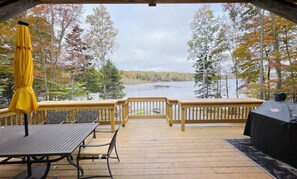 A wooden deck with a table and chairs, a grill, and a yellow umbrella. - Spacious Pocono Lakefront Retreat w/ Amenities (pocono lake)