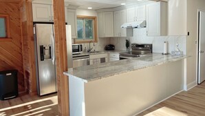 Una cocina moderna con armarios blancos, electrodomésticos de acero inoxidable y encimera de mármol.