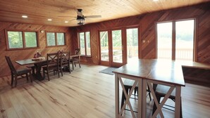 Una habitación espaciosa con techo de madera, ventanas amplias y un comedor con mesa y sillas.