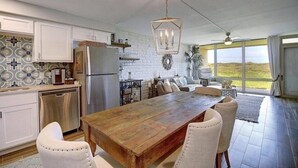 Una cocina amplia con armarios blancos, una mesa de comedor de madera y un ventanal con vistas al exterior.