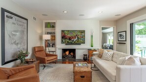 Una sala de estar con chimenea, un sofá, una mesa de centro y un cuadro de un caballo.