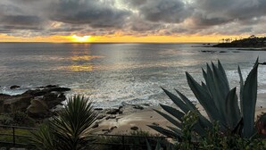 Vista de un atardecer costero con costa rocosa y vegetación.