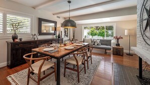 Un comedor con mesa de madera, sillas y una lámpara colgante.