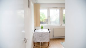 A room with a marble table, a potted plant, and a window with a view of greenery. - Large Shoreditch, Hoxton 3-Bed Garden Flat (London)
